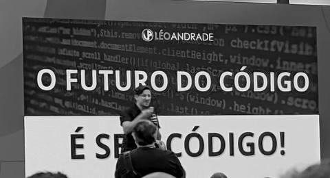 Léo Andrade no palco, diante do telão com a frase “O futuro do código é sem código”
