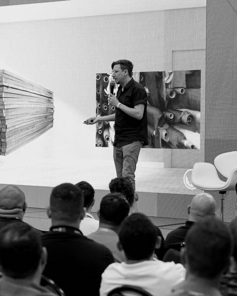 Léo Andrade palestrando no Elgin Tech Day 2023, de microfone na mão, diante de uma plateia cheia